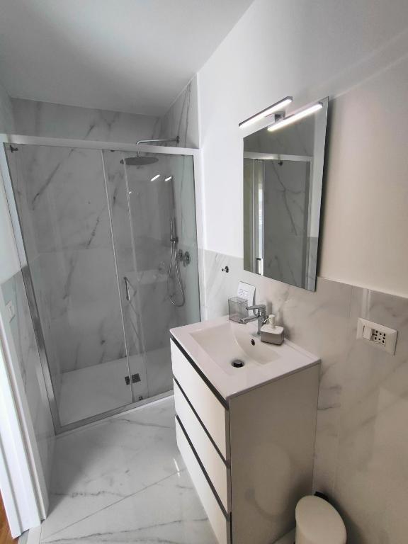 biała łazienka z prysznicem i umywalką w obiekcie Flavi Home B&B w Katanii