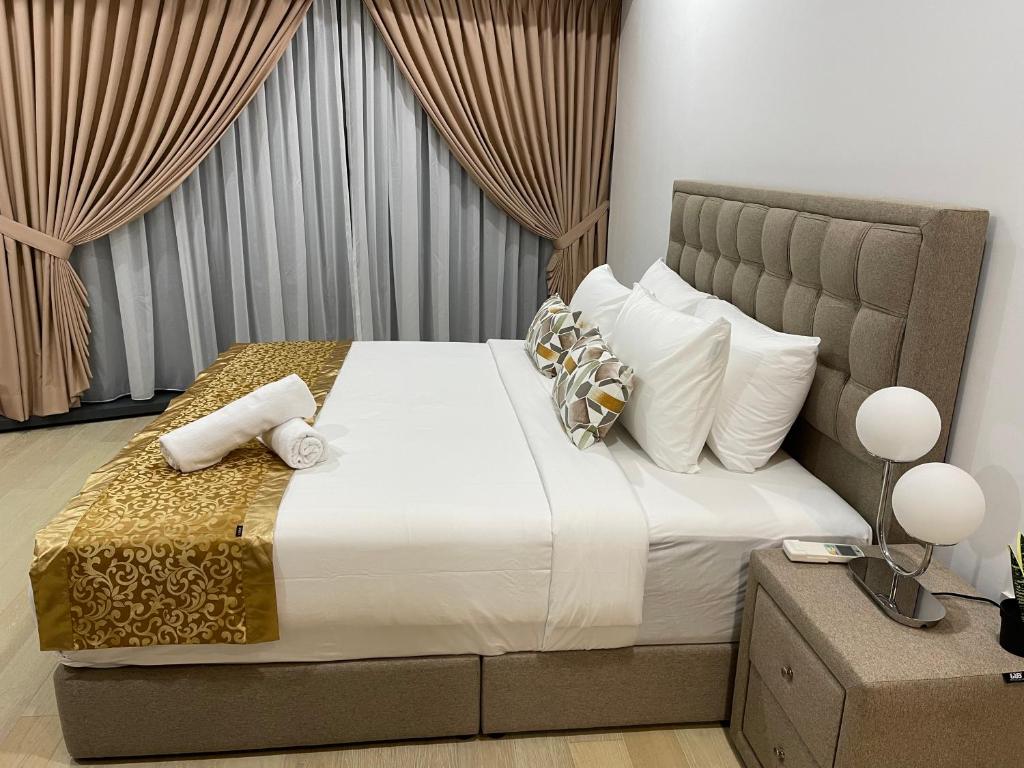 1 dormitorio con 1 cama grande con sábanas y almohadas blancas en Eaton Residences KLCC by Luna en Kuala Lumpur