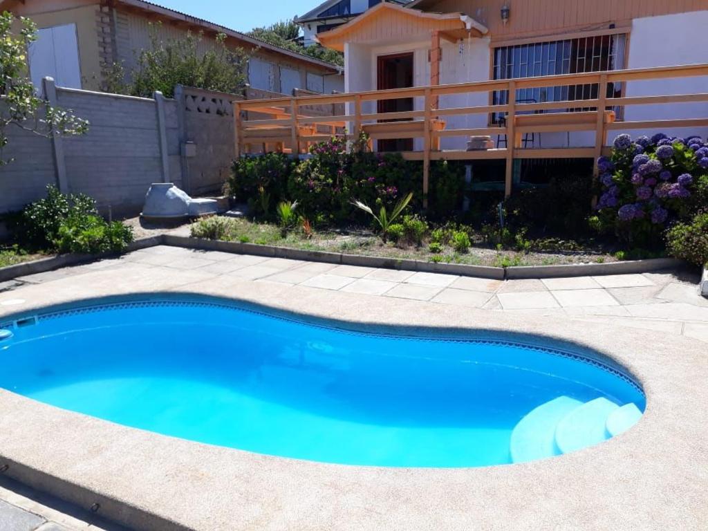 une piscine bleue en face d'une maison dans l'établissement Linda casa con piscina en el quisco., à El Quisco