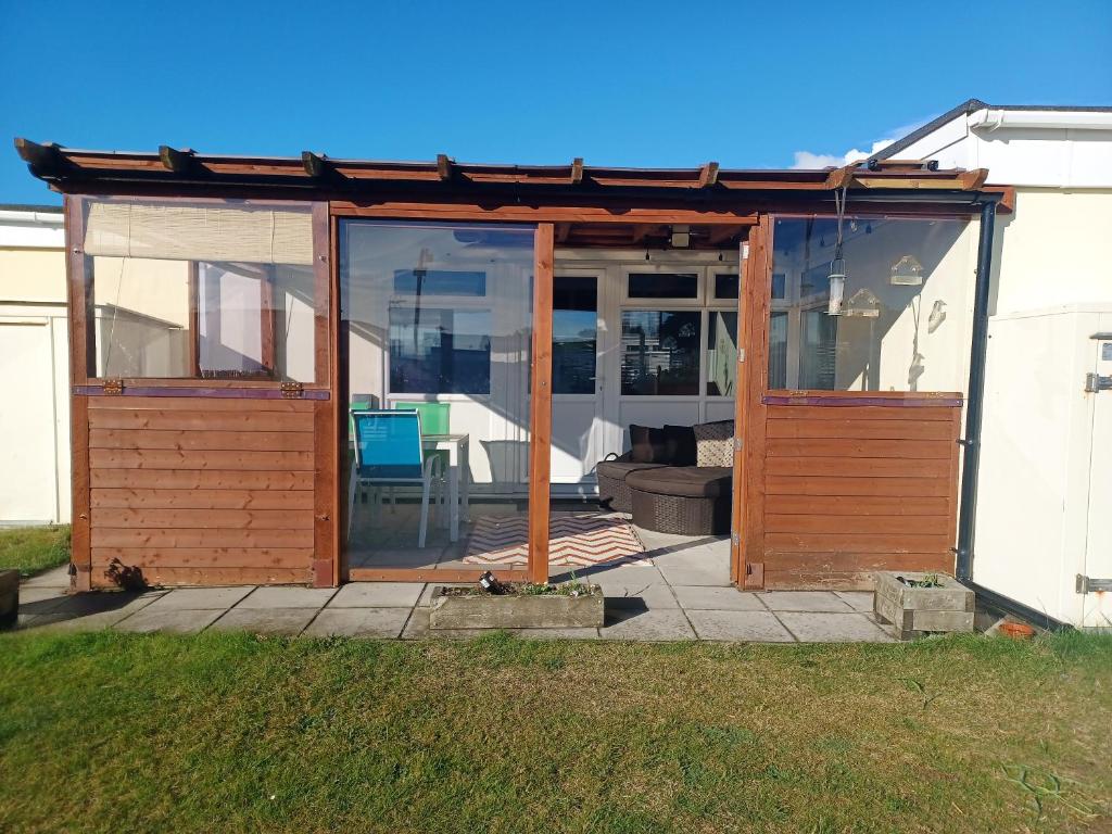 a wooden pergola with glass doors on a patio at 2-bedroom Holiday Home With Great Outdoor Space in Kidwelly
