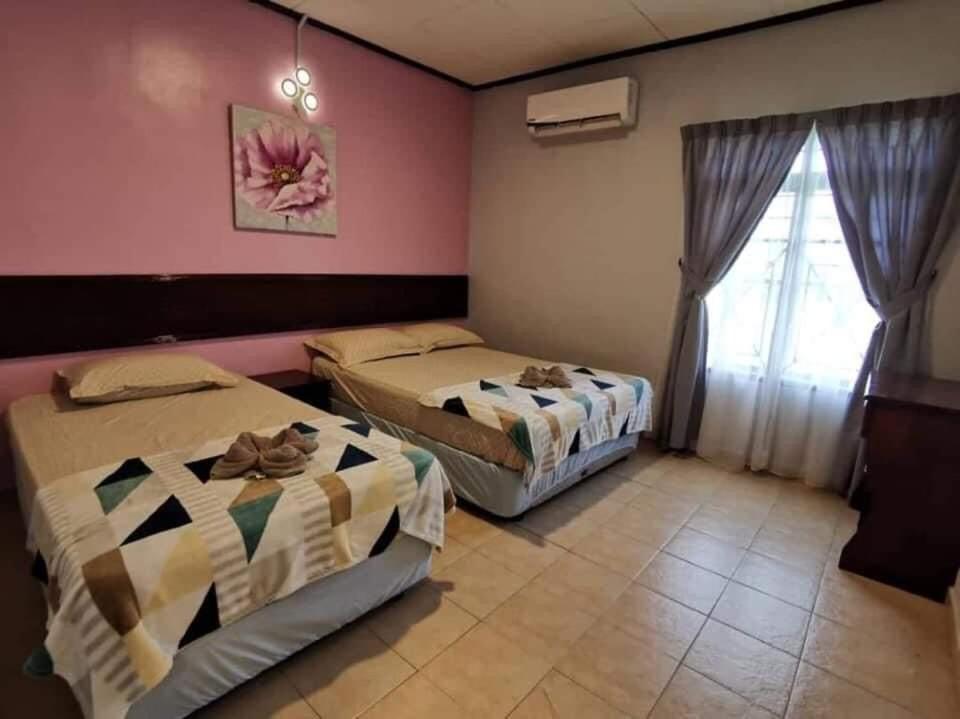 two beds in a room with a window at SB PRIMA VILLA APRTMENT in Tanah Rata