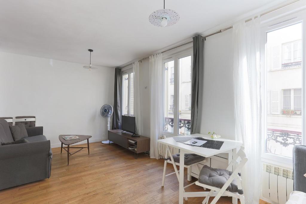 sala de estar con sofá, escritorio y ventanas en Eiffel Tower Royal Apartment, en París
