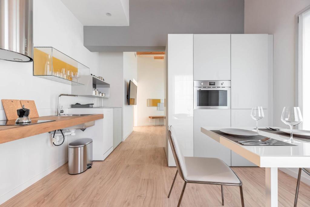 a kitchen with white cabinets and a table with a chair at Palazzo '900 Design Flats - L'Orologiaio in Padova