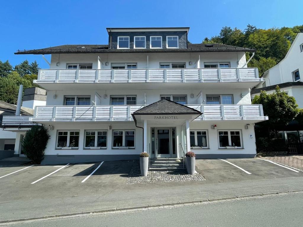 a large white building with a parking lot at Parkhotel Schmallenberg in Schmallenberg