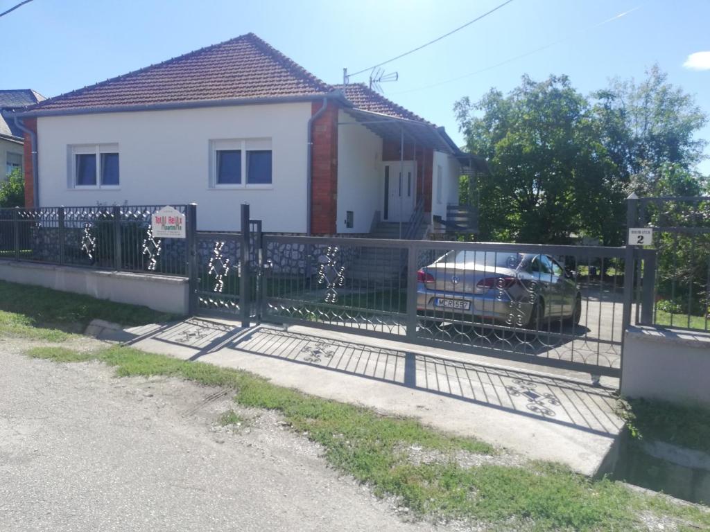 a fence in front of a house with a car at Total Relax Apartmanház in Bogács