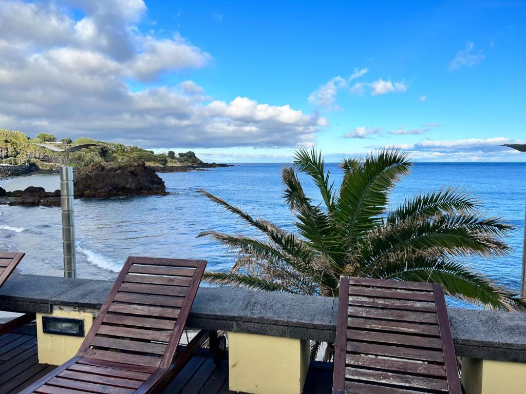 two chairs sitting on a balcony looking at the ocean at Vinha da Areia Beach Hotel in Vila Franca do Campo