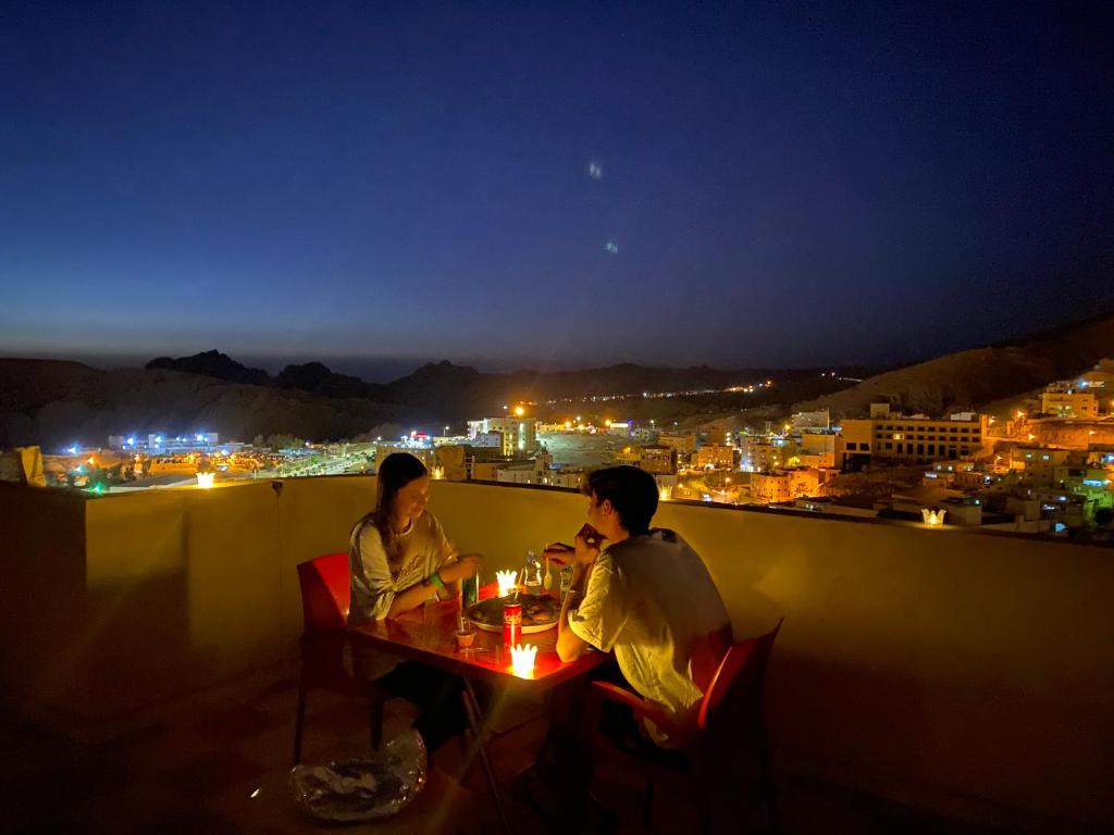 two people sitting at a table on a balcony at night at Hustle's look in Wadi Musa