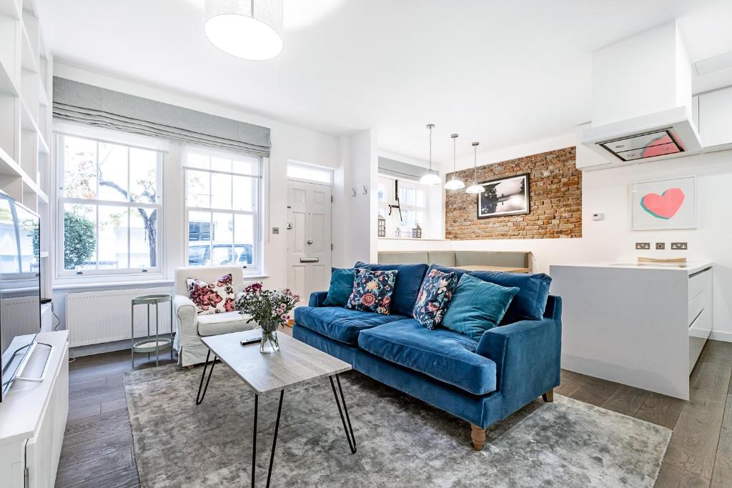 uma sala de estar com um sofá azul e uma cozinha em London Choice Apartments - South Kensington - Mews House em Londres