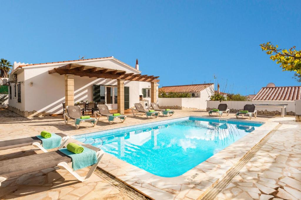 uma piscina com cadeiras e uma casa em Villa Ingrid Porter by Villa Plus em Cala'n Porter