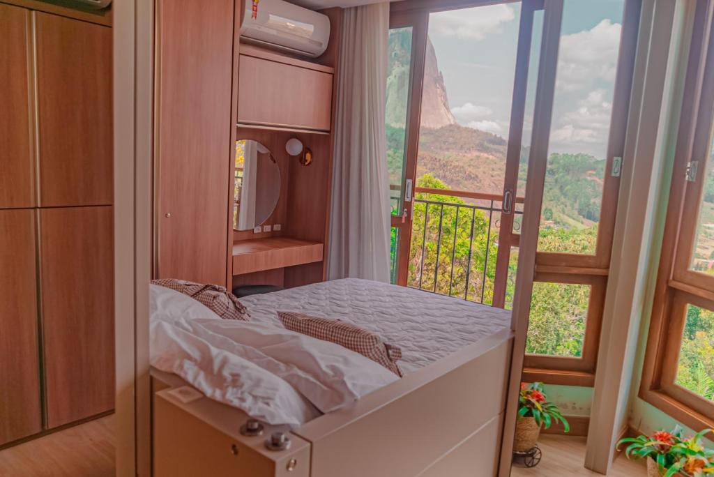 a small bed in a room with a balcony at Blue Flat Pedra Azul - Com Vista pra Pedra in Pedra Azul