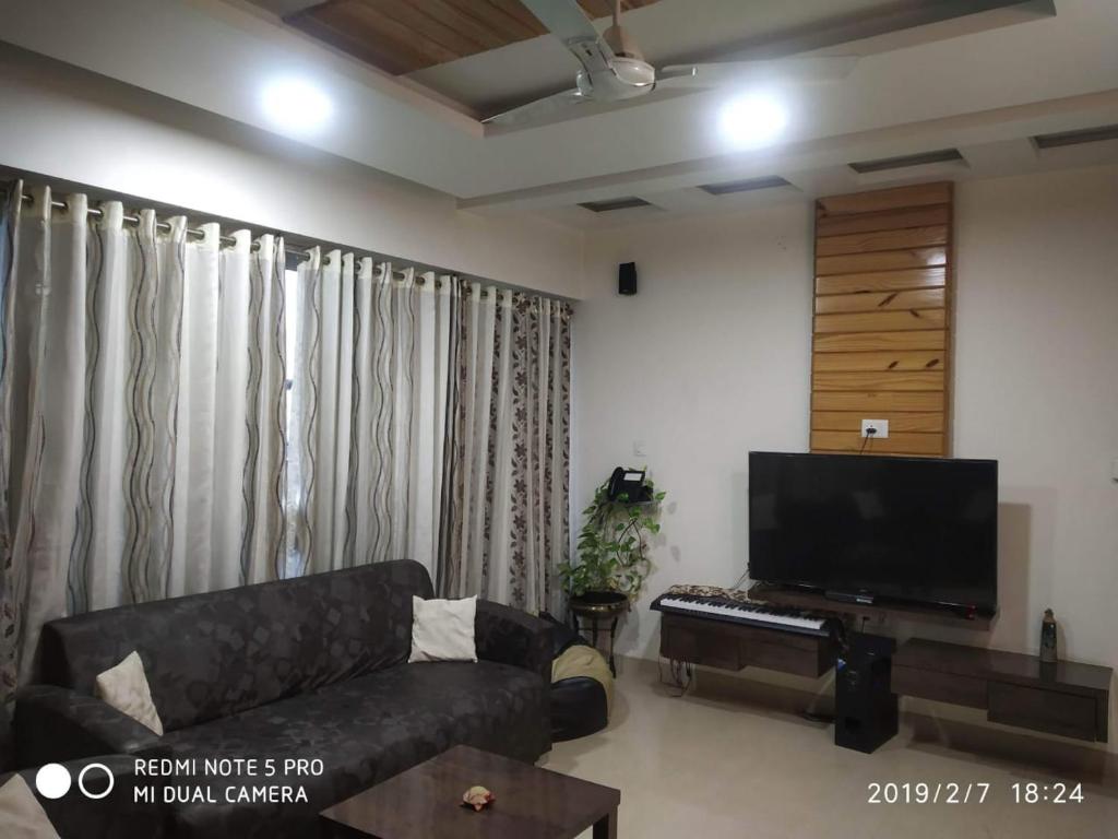 ein Wohnzimmer mit einem Sofa und einem Flachbild-TV in der Unterkunft Royal Suites - 3 rooms Appt -Blue in Pune