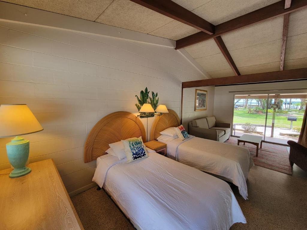 a bedroom with two beds and a couch and a window at Tropical Marina & Resort on Lake Beresford in DeLand