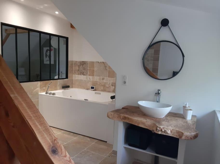 een badkamer met een bad, een wastafel en een spiegel bij Appartement chaleureux avec Jacuzzi in Banassac