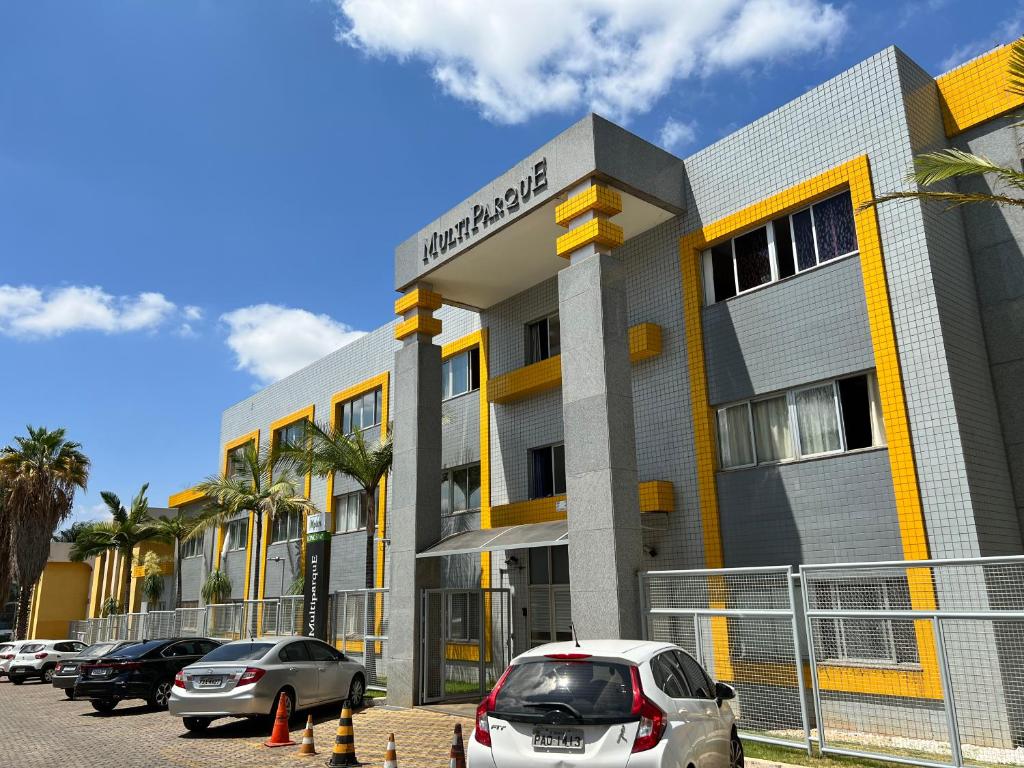 um edifício com carros estacionados em frente em Multiparque Hplus Long Stay em Brasília