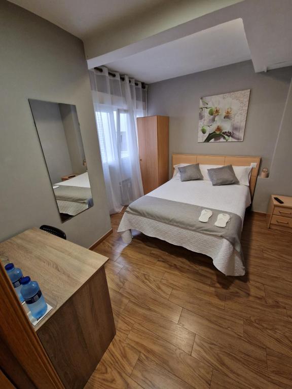 - une chambre avec un grand lit et un miroir dans l'établissement Hostal Fidalgo, à Oviedo