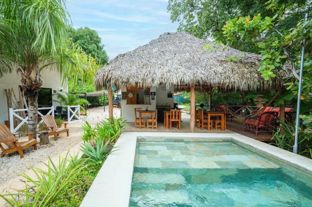 a villa with a swimming pool and a hut at Antema Lodge Secteur Tamarindo, piscine, yoga, gym, jungle et paix in Tamarindo