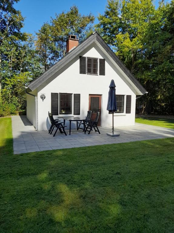 uma casa branca com um pátio e um guarda-chuva em Skovhuset em Give