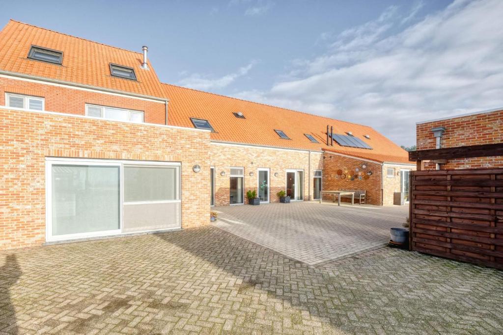 a brick house with an orange roof and a courtyard at Hoeve Megusta in Vlimmeren