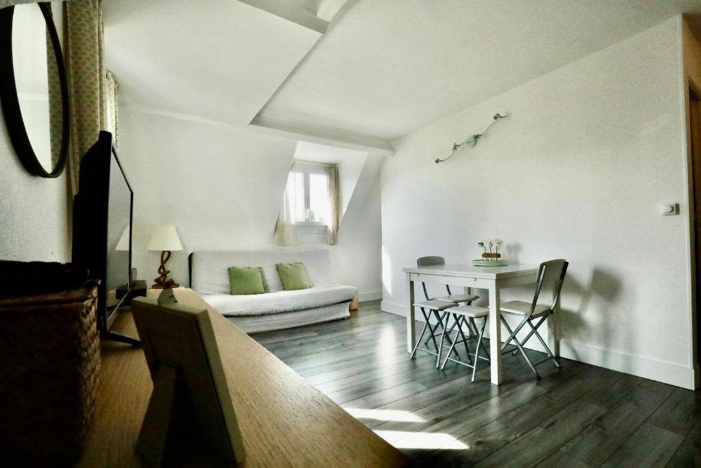 a living room with a table and a couch at Appartement de l'Hippodrome avec deux chambres in Deauville