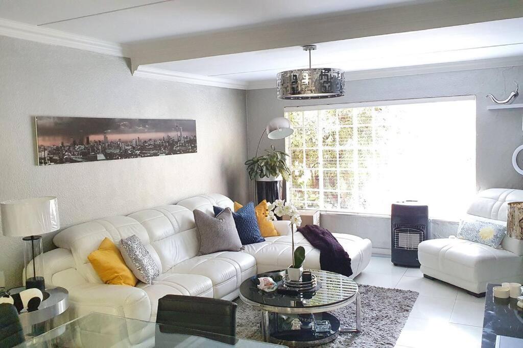 sala de estar con sofá blanco y mesa de cristal en Upmarket 3 Bedroom Apartment, en Johannesburgo