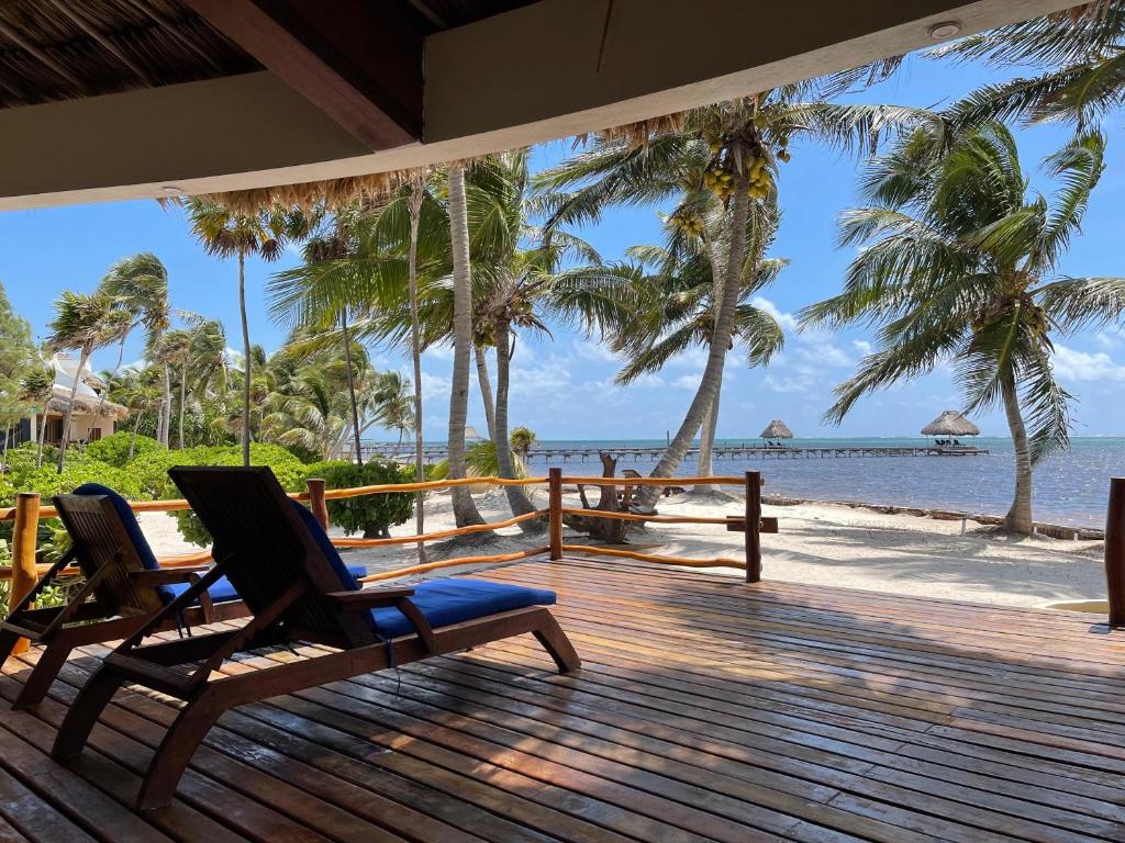 two chairs sitting on a deck looking at the beach at La Perla del Caribe - Villa Sand in San Pedro