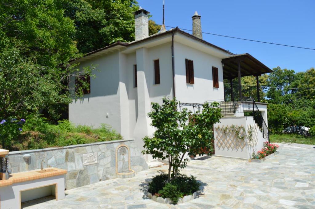 Una casa blanca con un árbol delante. en Villa Consta, en Tsagkarada