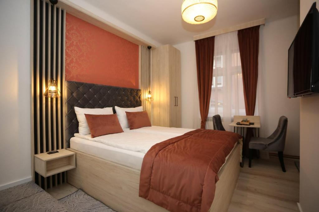 a hotel room with a large bed and a desk at Apartments Artee Free Garage Parking in Sarajevo
