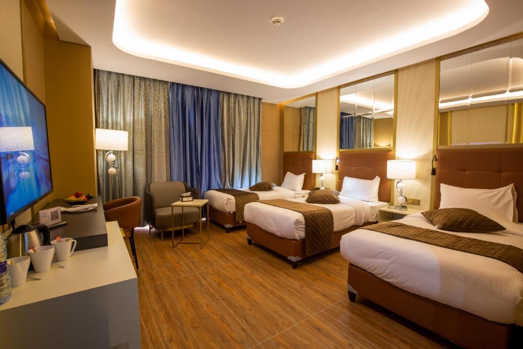 Habitación de hotel con 2 camas y escritorio en Petra Moon Luxury Hotel, en Wadi Musa