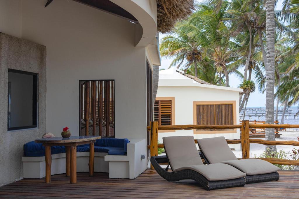 patio z 2 krzesłami, stołem i palmami w obiekcie La Perla del Caribe - Villa Sapphire w mieście San Pedro