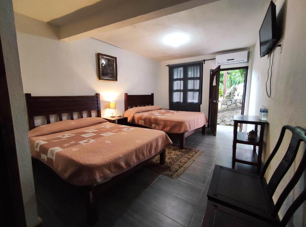 una camera d'albergo con due letti e una televisione di FINCA QUINTA LOS CEDROS a Xilitla