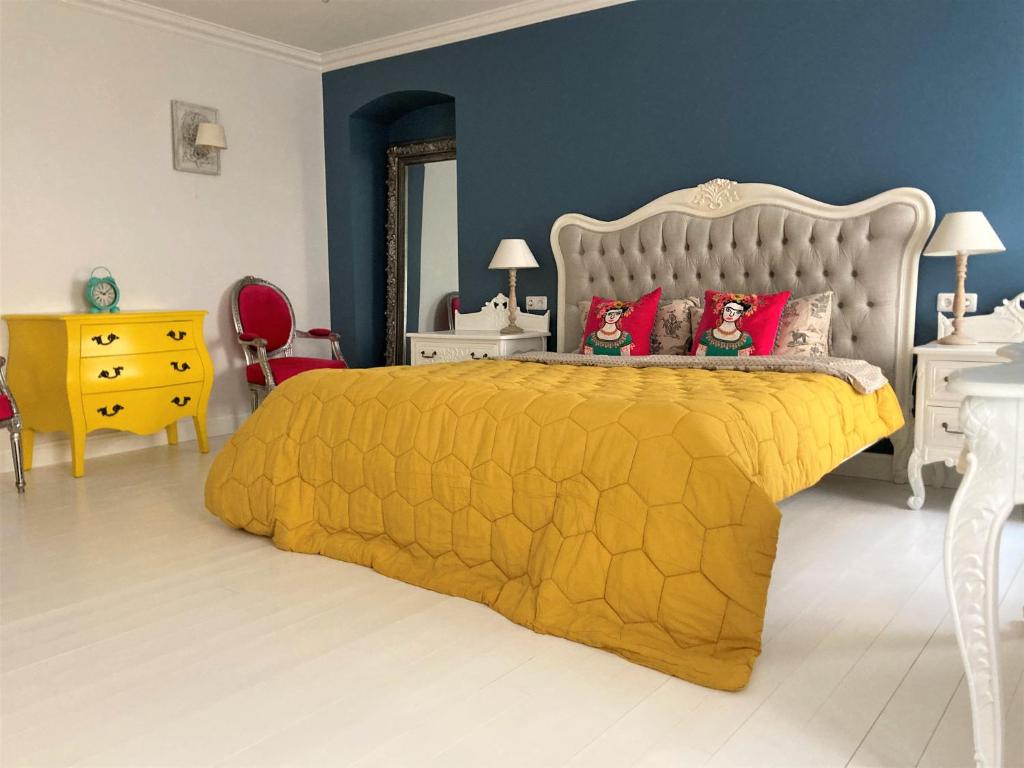 a bedroom with a yellow bed with red pillows at Shabby Chic - apartment in the Heart of Vilnius Old Town in Vilnius