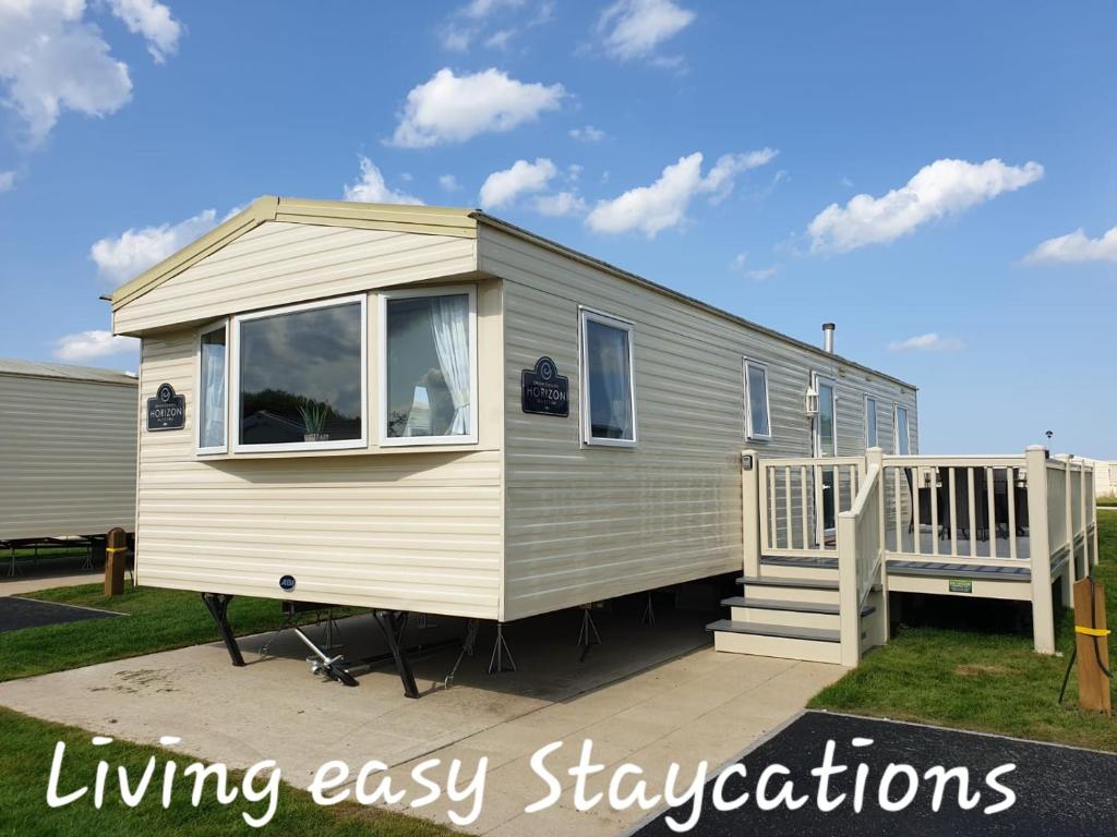 a tiny house with a porch and a staircase at Living Easy Staycations at Tattershall Lakes in Tattershall