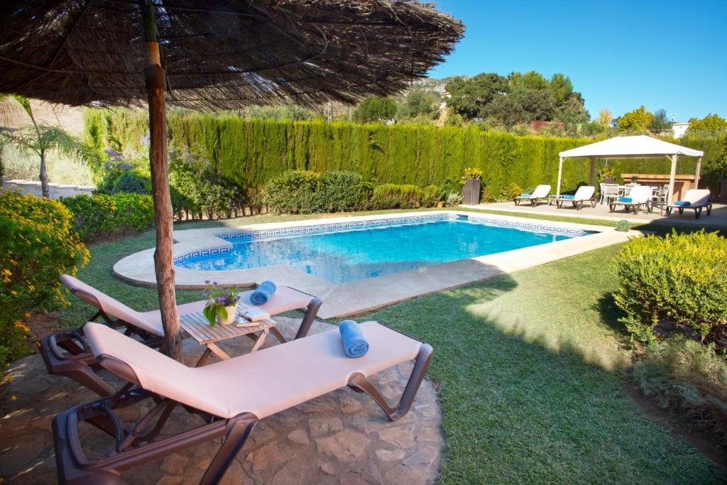 una piscina con 2 sillas y una sombrilla en Casa Rural Los Niños, en Algodonales