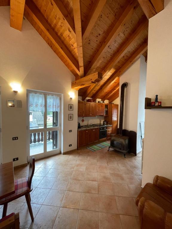 uma ampla sala de estar com tectos em madeira e uma cozinha em Attico sul Rosa em Ceppo Morelli