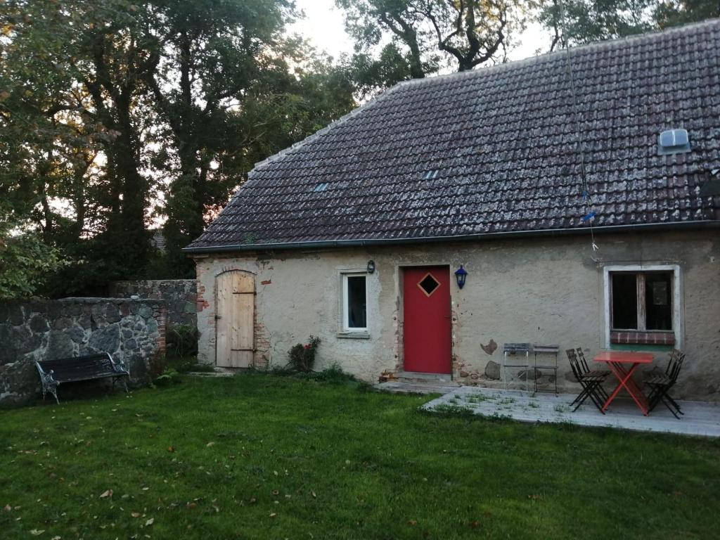 una pequeña casa blanca con una puerta roja en Ferienhaus Woddow Uckermark en Woddow