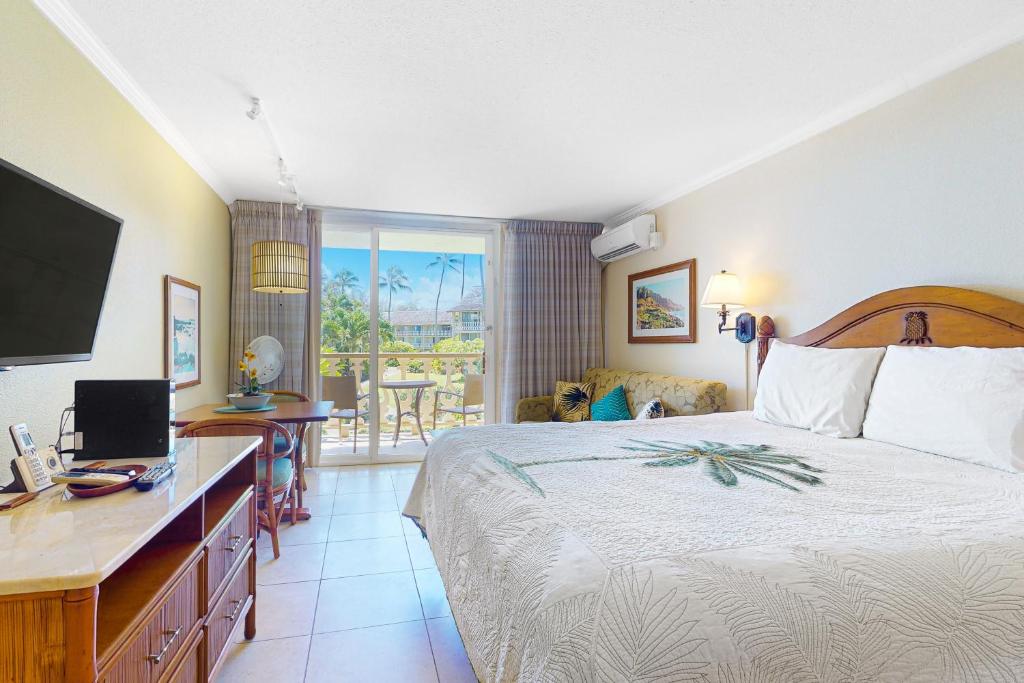 a bedroom with a bed and a desk with a television at Islander on the Beach 235 in Kapaa