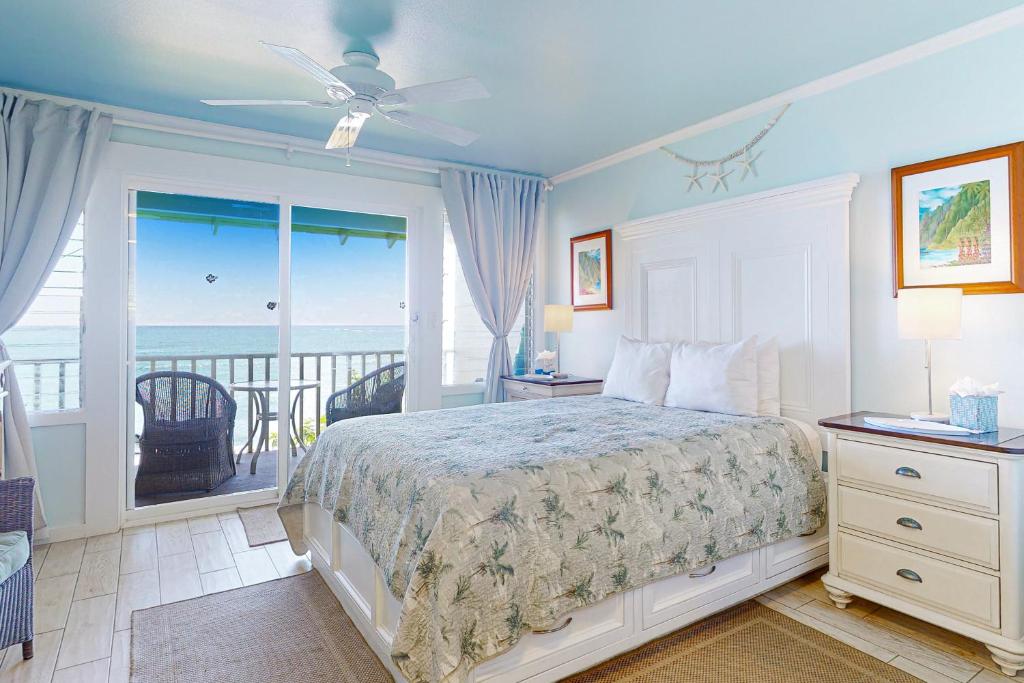 a bedroom with a bed and a balcony with the ocean at Kapa'a Sands 09 in Kapaa