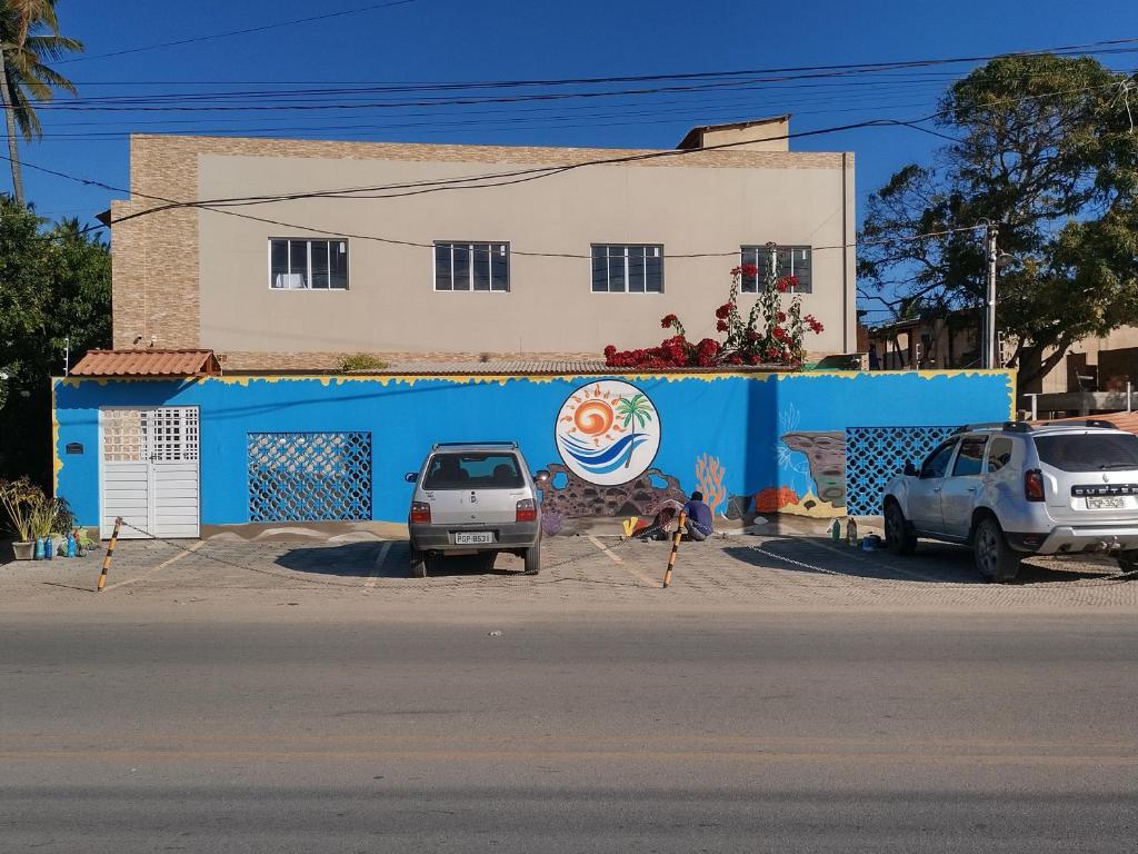 two cars parked in front of a blue building at Peroba Mar Kitnets in Maragogi