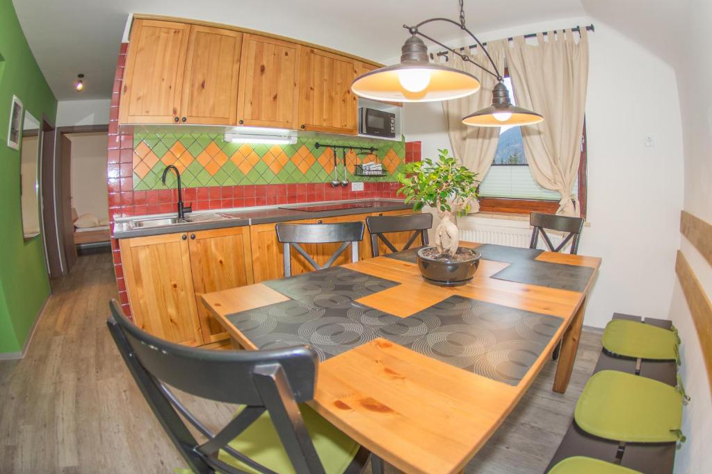 cocina con mesa de madera y sillas verdes en Apartments Helena Kranjska Gora en Kranjska Gora