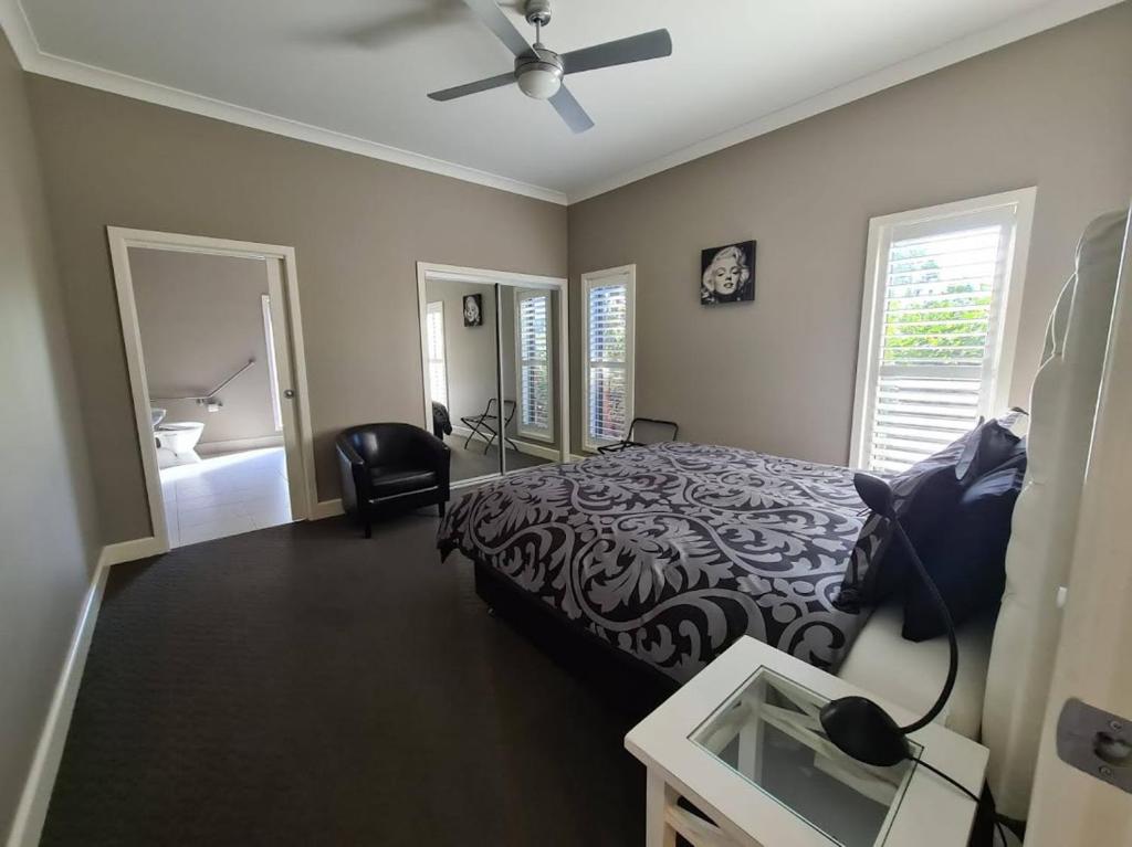 a bedroom with a bed and a ceiling fan at Barklysuites Apartments in Rutherglen