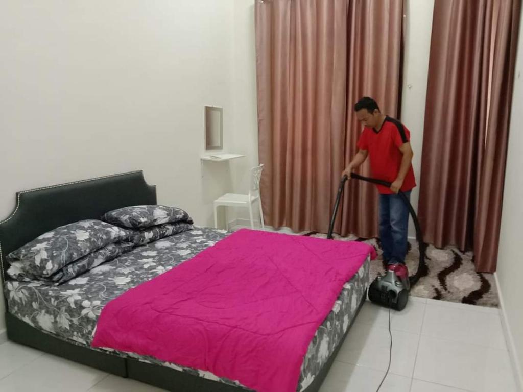 大港的住宿－Homestay Dorani Sungai Besar，吸尘器清洁卧室,卧室配有床
