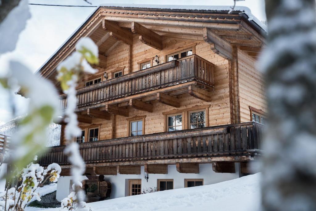 a wooden house with a balcony in the snow at Oberschupferhof in Außervillgraten