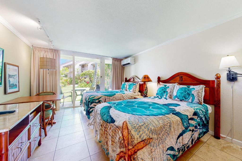 a bedroom with two beds and a desk at Islander on the Beach 157 in Kapaa