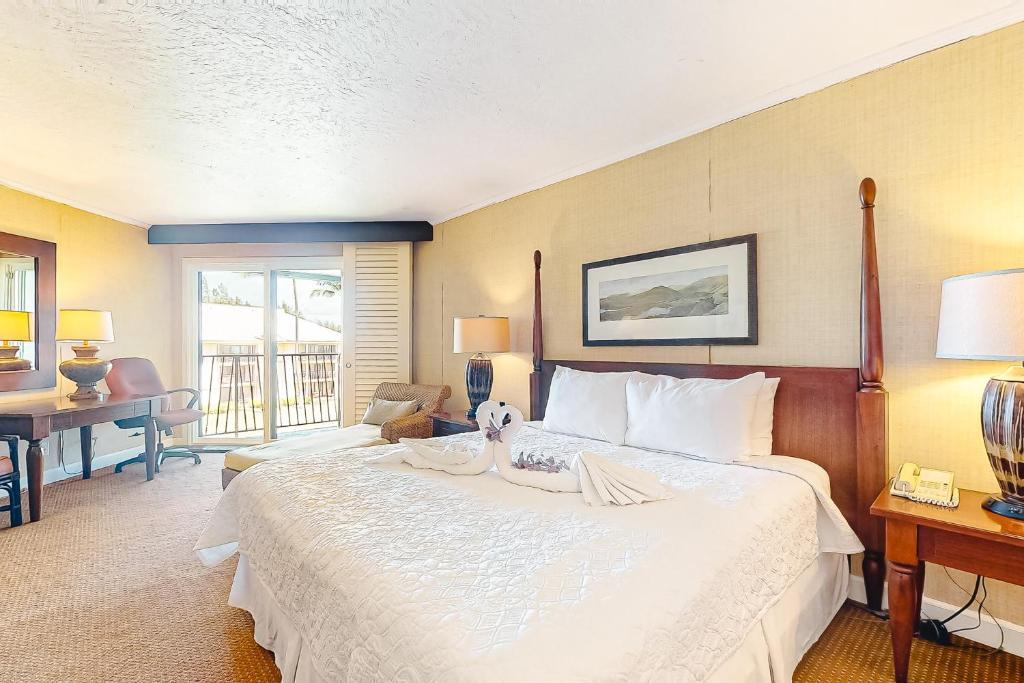 a bedroom with a large white bed and a desk at Kauai Beach Resort #1317 in Lihue