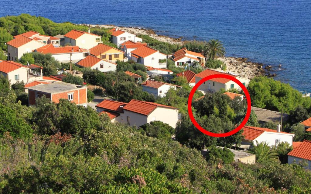 a house with a red circle in the middle of a village at Apartments by the sea Milna, Vis - 8943 in Rukavac