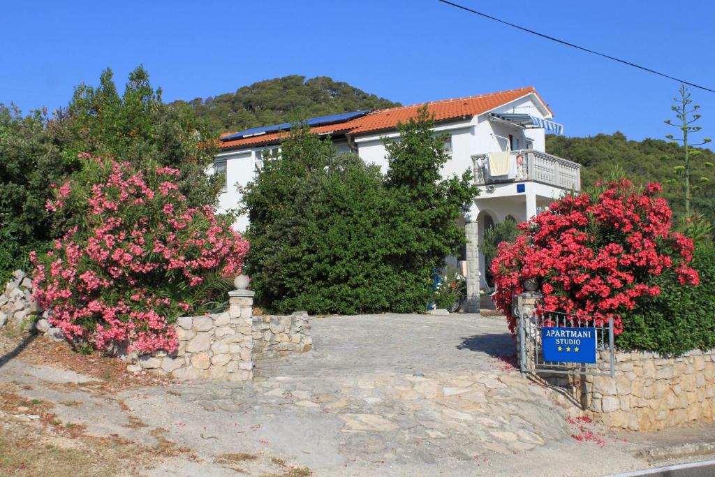 a white house with pink flowers in front of it at Apartments with a parking space Preko, Ugljan - 8224 in Preko