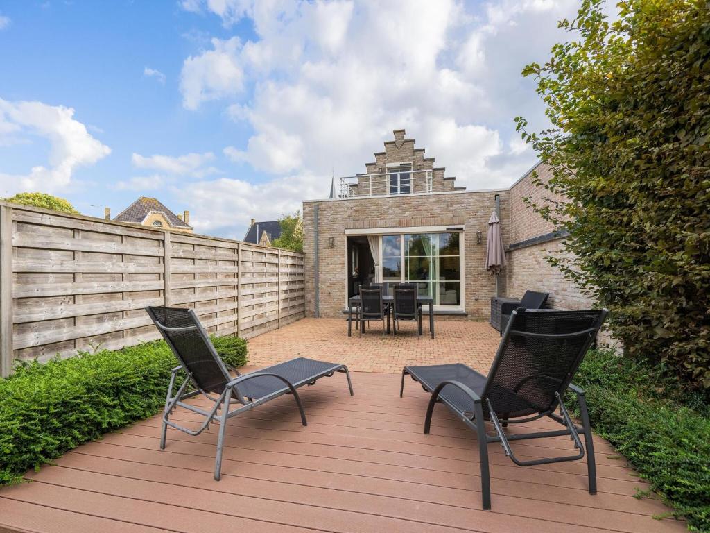 une terrasse avec des chaises, une clôture et une maison dans l'établissement Inviting holiday home in Nieuwpoort with private garden, à Nieuport