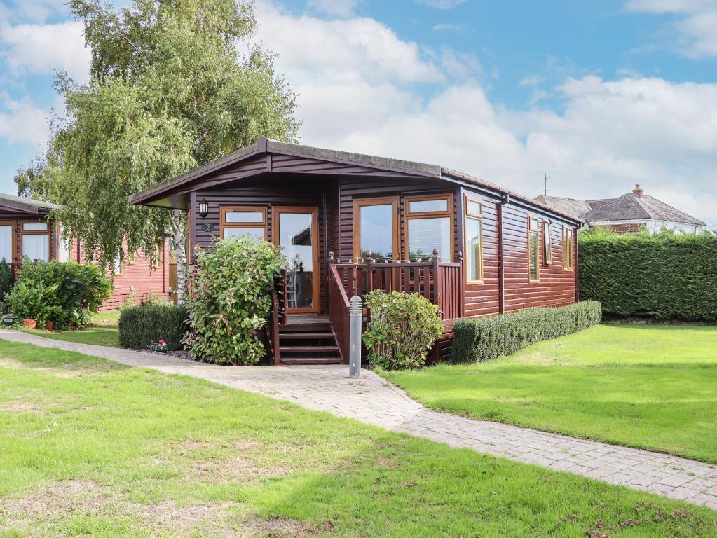 a wooden cabin with a porch in a yard at Lodge Two, Country View Park in Faversham