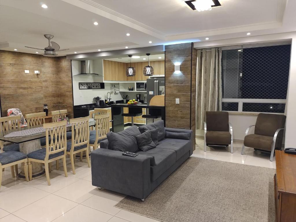 Il comprend un salon et une cuisine avec un canapé et une table. dans l'établissement Apartamento Avenida da Praia Centro Caraguatatuba, à Caraguatatuba