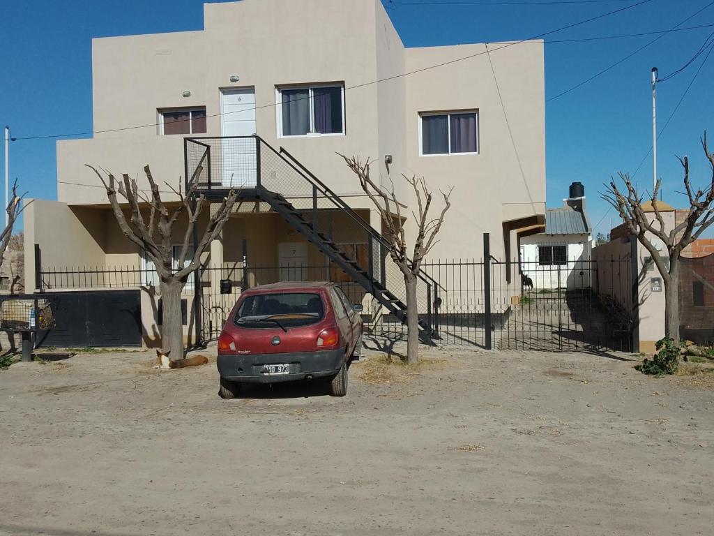 une petite voiture rouge garée devant un immeuble dans l'établissement Alquiler por día Choele Choel 3, à Choele Choel